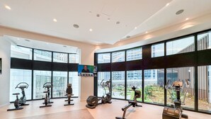 Et moderne fitnesscenter med varieret træningsudstyr, store vinduer og udsigt over byen.