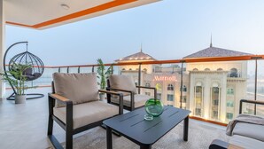 Un balcón con mobiliario, una mesa de vidrio y vistas a un edificio con un cartel que dice 'Marriott'.