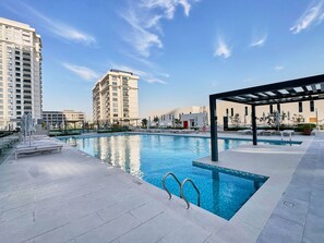 Ein Dachpool mit blauem Himmel, Liegestühlen und einer Pergola.