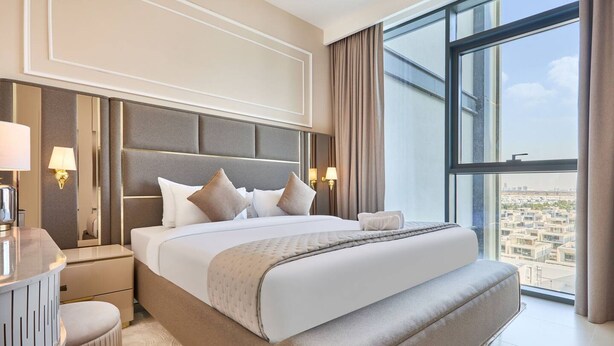 Moderni hotellihuone, jossa on suuri sänky, yöpöydät, peilipöytä ja näkymä kaupunkiin.