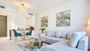 Ein modernes Wohnzimmer mit einer Couch, einem Couchtisch und zwei Sesseln. Im Hintergrund ist eine Küche zu sehen.