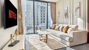 A modern living room with a large flat-screen TV, a sofa, a coffee table, and a view of high-rise buildings. - The Crest C Luxury Retreat Stylish Serene (Dubai)