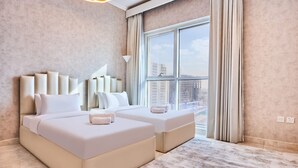 A modern hotel room with a large window, two beds, and a city view. - 2 Bedroom Apartment Close to Miracle Tower (Dubai)
