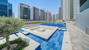 A modern urban setting with a swimming pool, high-rise buildings, and a clear sky. - Classic Arabian Elegance With City Views (Dubai)