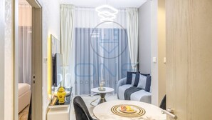 Ett modernt hotellrum med en matplats, en soffa, en tv och ett fönster med gardiner.