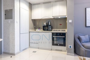 A modern kitchen with built-in appliances, a microwave, toaster, and oven. - Cozy One Bedroom Apartment in Zada Tower (Dubai)