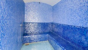 A blue-tiled shower area with a bench and a showerhead. - 1BR Zada Tower l Two Balconies City Views (Dubai)