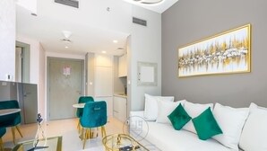 A modern living room with a white sofa, teal chairs, a glass coffee table, and a painting on the wall. - 1BR Zada Tower l Two Balconies City Views (Dubai)