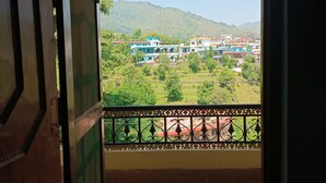 Ein Balkon mit gemustertem Boden, Blick auf eine grüne Landschaft und ein Gebäude mit farbenfrohen Fassaden.
