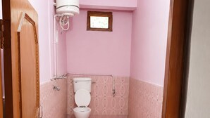 Ein kleines Badezimmer mit rosa Wänden, einer Toilette, einer Dusche und einem weißen Durchlauferhitzer an der Wand.