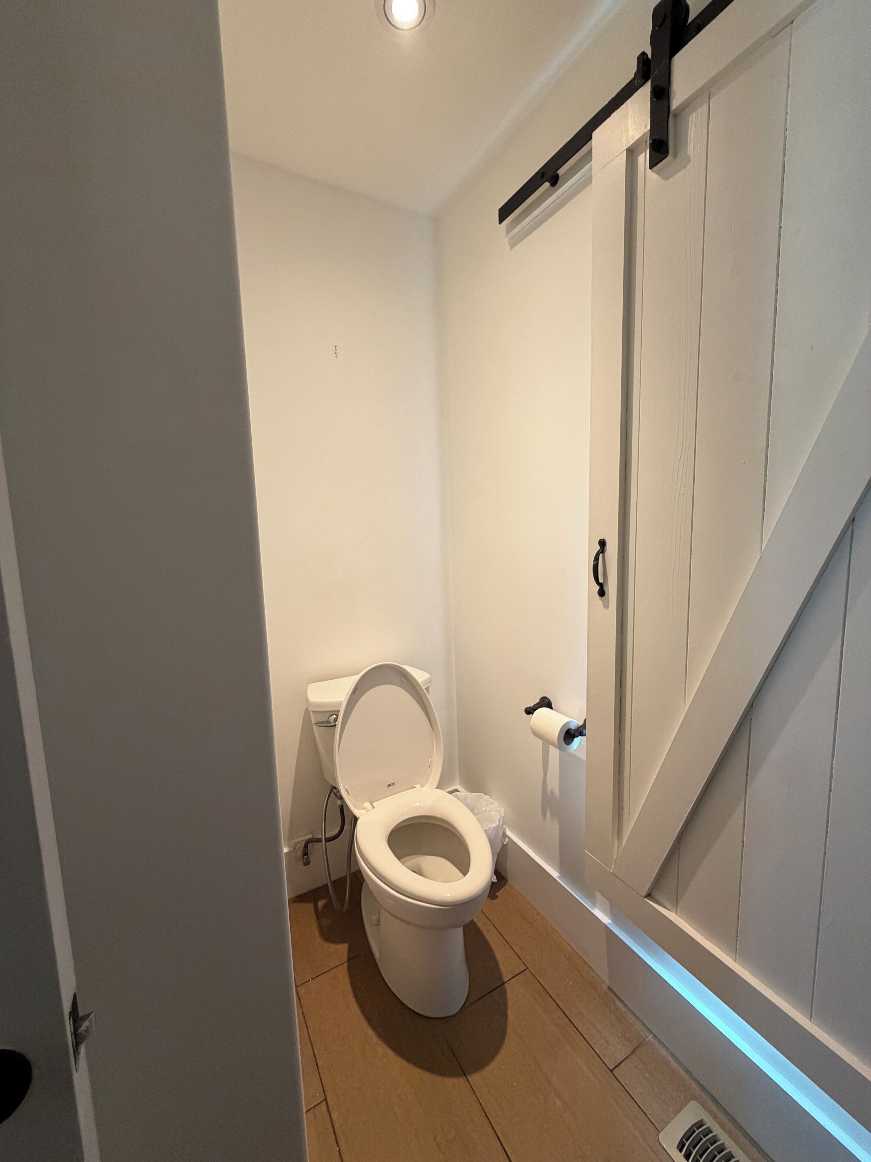 Un baño con inodoro, ducha y puerta con pomo negro.