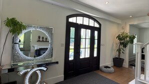 Un salon moderne avec un grand miroir, une porte noire et un escalier.