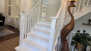 Un escalier avec des rampes blanches et un luminaire sculptural unique.