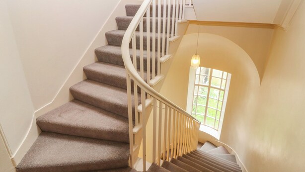 A spiral staircase with carpeted steps and white railings. - Pincerna Apartment Suite 1a (Aberdeen)