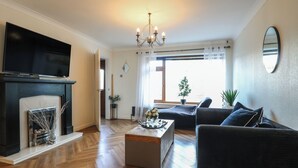 Una sala de estar con chimenea, televisor, candelabro y sofá.