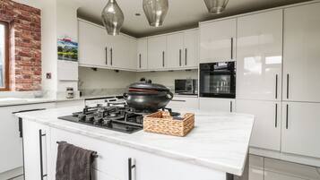 A modern kitchen with white cabinets, a central island with a stove, a microwave, and an oven.