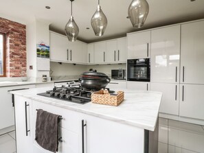 A modern kitchen with white cabinets, a central island with a stove, a microwave, and an oven. - 57 Howden Avenue (Doncaster)