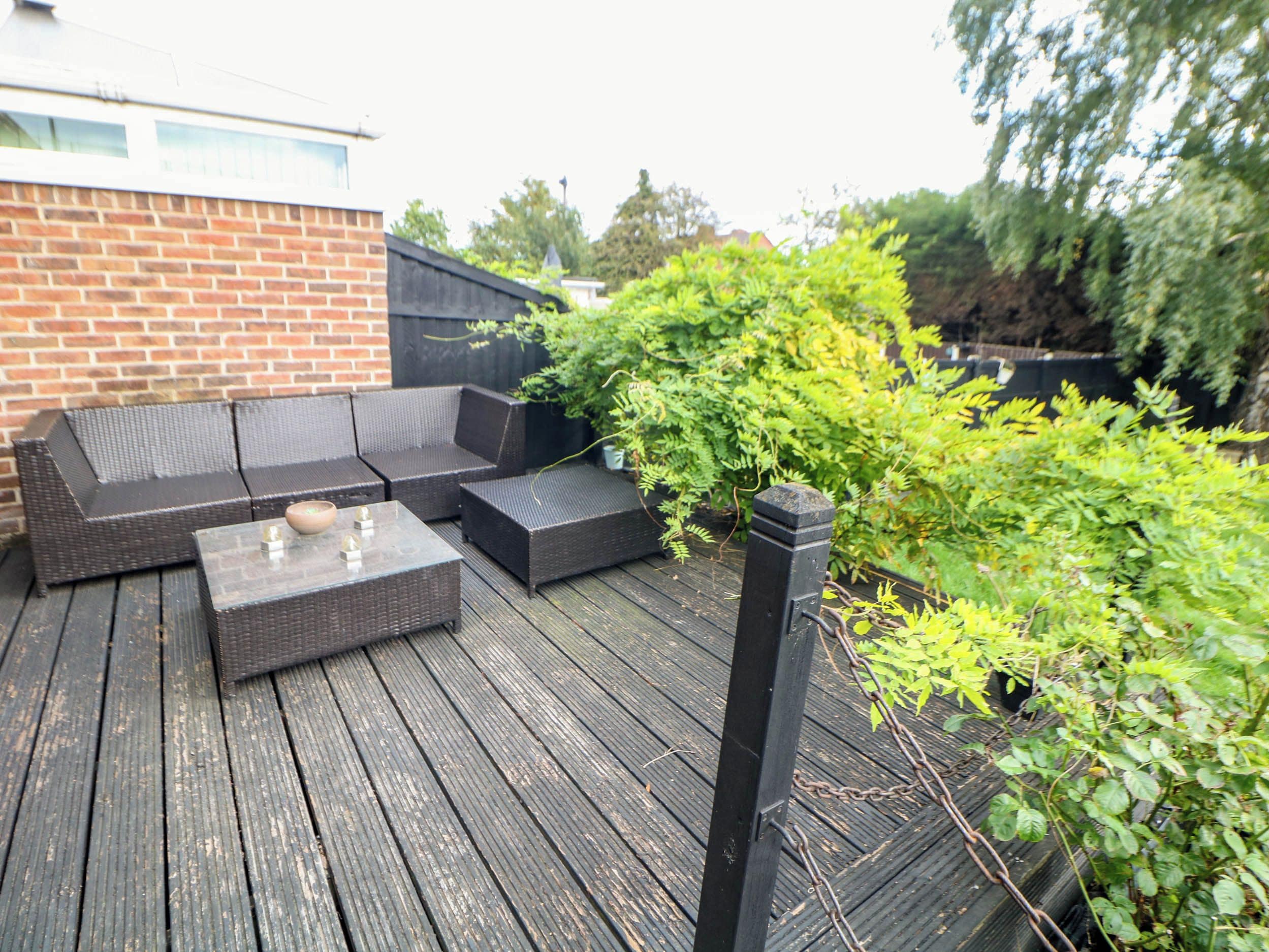 Eine Terrasse mit Gartenmöbeln, darunter Sofas und ein Couchtisch.