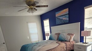 A bedroom with a bed, a nightstand, a desk, a ceiling fan, and a window. - Coastal Retreat/ 2BR/2BA Split Floor Plan / Minutes to Anna Maria Island & Beach (Bradenton)