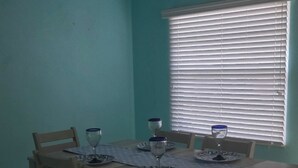 A dining area with a table set for four, a ceiling fan, and a window with blinds. - Coastal Retreat/ 2BR/2BA Split Floor Plan / Minutes to Anna Maria Island & Beach (Bradenton)