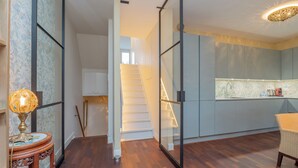Eine moderne Küche mit weißer Wendeltreppe, einem Essbereich mit einem Stuhl und einer dekorativen Lampe.