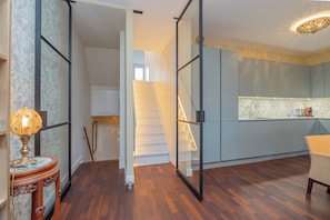 A modern kitchen with a white staircase, a dining area with a chair, and a decorative lamp. - A Sumptuous Canal Penthouse on the Emperor's Canal in Amsterdam! (Amsterdam)