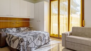 A bedroom with a bed, a sofa, a wardrobe, and a window with curtains. - Apartment 'La Dolce Vacanza' with Private Terrace, Wi-Fi and Air Conditioning (Desenzano del Garda)