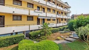 A multi-story building with balconies, a courtyard with greenery, and a clear sky. - Apartment 'La Dolce Vacanza' with Private Terrace, Wi-Fi and Air Conditioning (Desenzano del Garda)