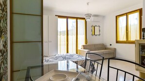 A modern living room with a glass dining table, a sofa, and a chandelier. - Apartment 'La Dolce Vacanza' with Private Terrace, Wi-Fi and Air Conditioning (Desenzano del Garda)