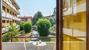 A balcony with two chairs and a table, overlooking a residential area with buildings and greenery. - Apartment 'La Dolce Vacanza' with Private Terrace, Wi-Fi and Air Conditioning (Desenzano del Garda)