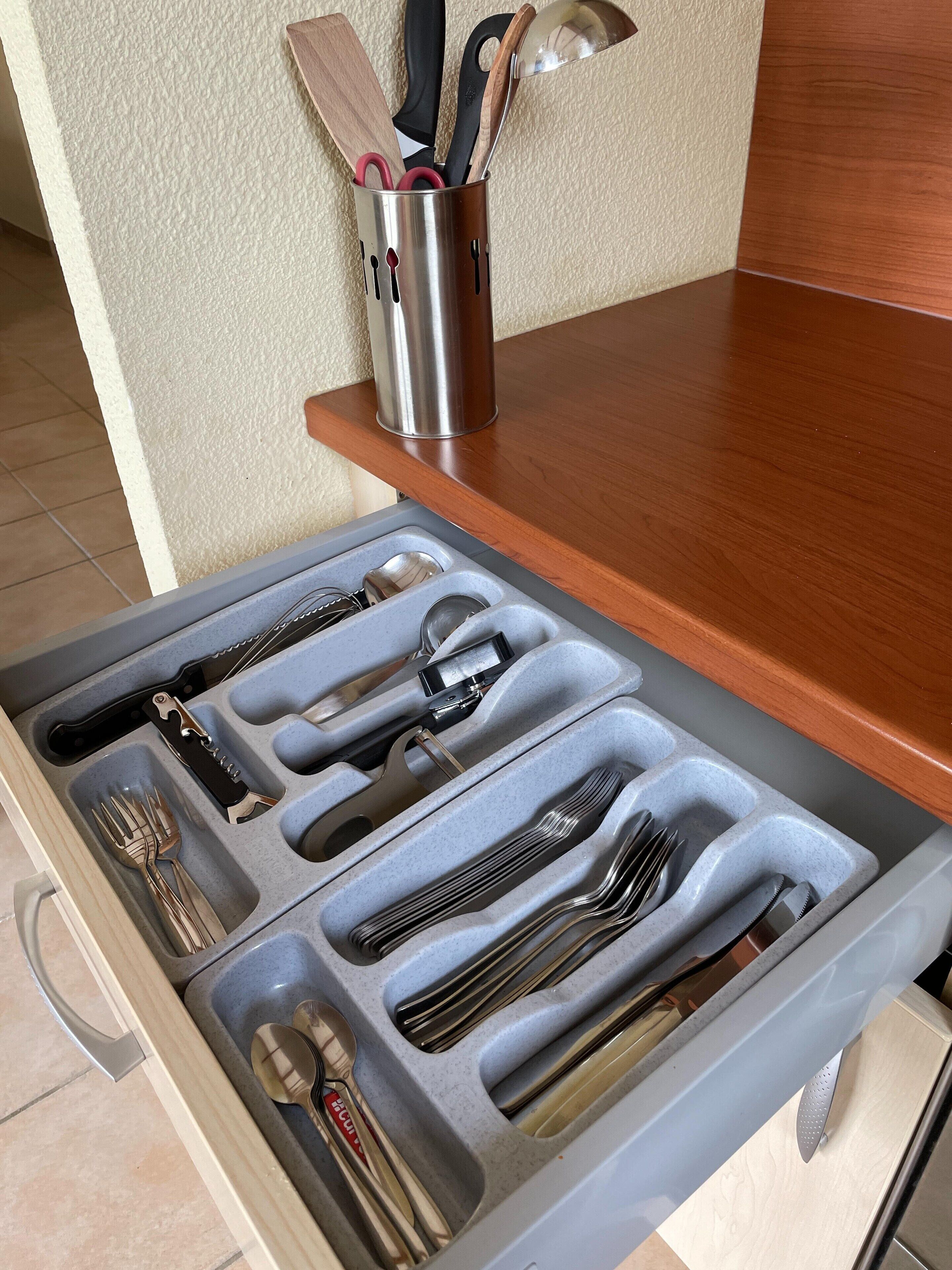Un cajón de cocina con utensilios y un juego de cuchillos.