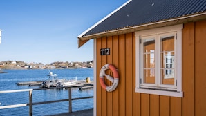 A wooden building with the number 1112, a lifebuoy, and a view of a dock with boats.