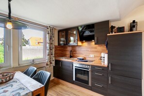 Una cocina compacta con horno integrado, cafetera y microondas.