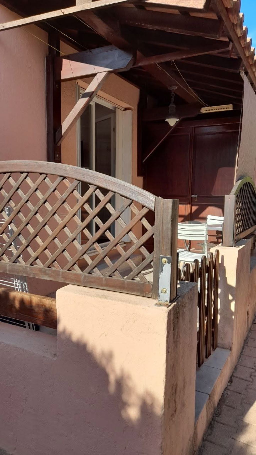 A wooden gate with a lattice design, a concrete base, and a metal latch.