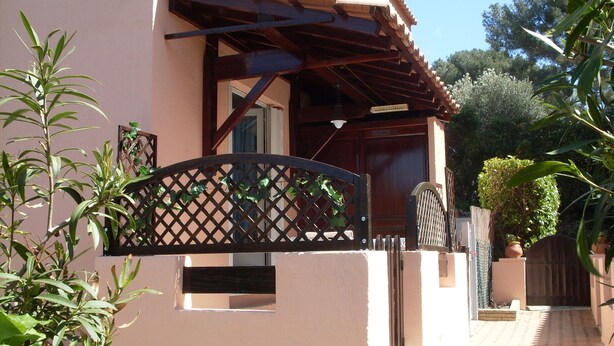 Ein Haus mit einer Holzpergola, einem Tor und einem gepflasterten Weg.