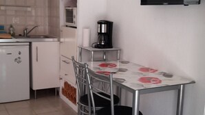 Eine kleine Küche mit Esstisch, Stühlen, einer Kaffeemaschine und einer Mikrowelle.