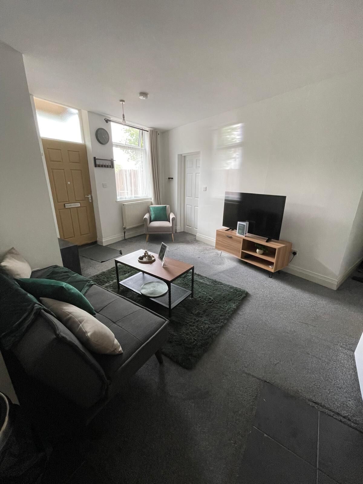 Ein Wohnzimmer mit einer Couch, einem Couchtisch, einer TV-Konsole und einem Sessel.