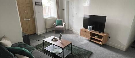 A living room with a sofa, coffee table, TV stand, and a chair.
