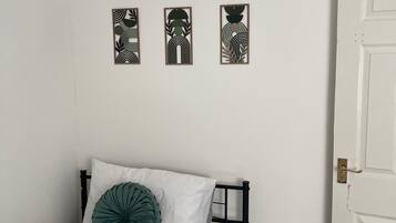A bedroom with a bed, a door, and three wall-mounted artworks.