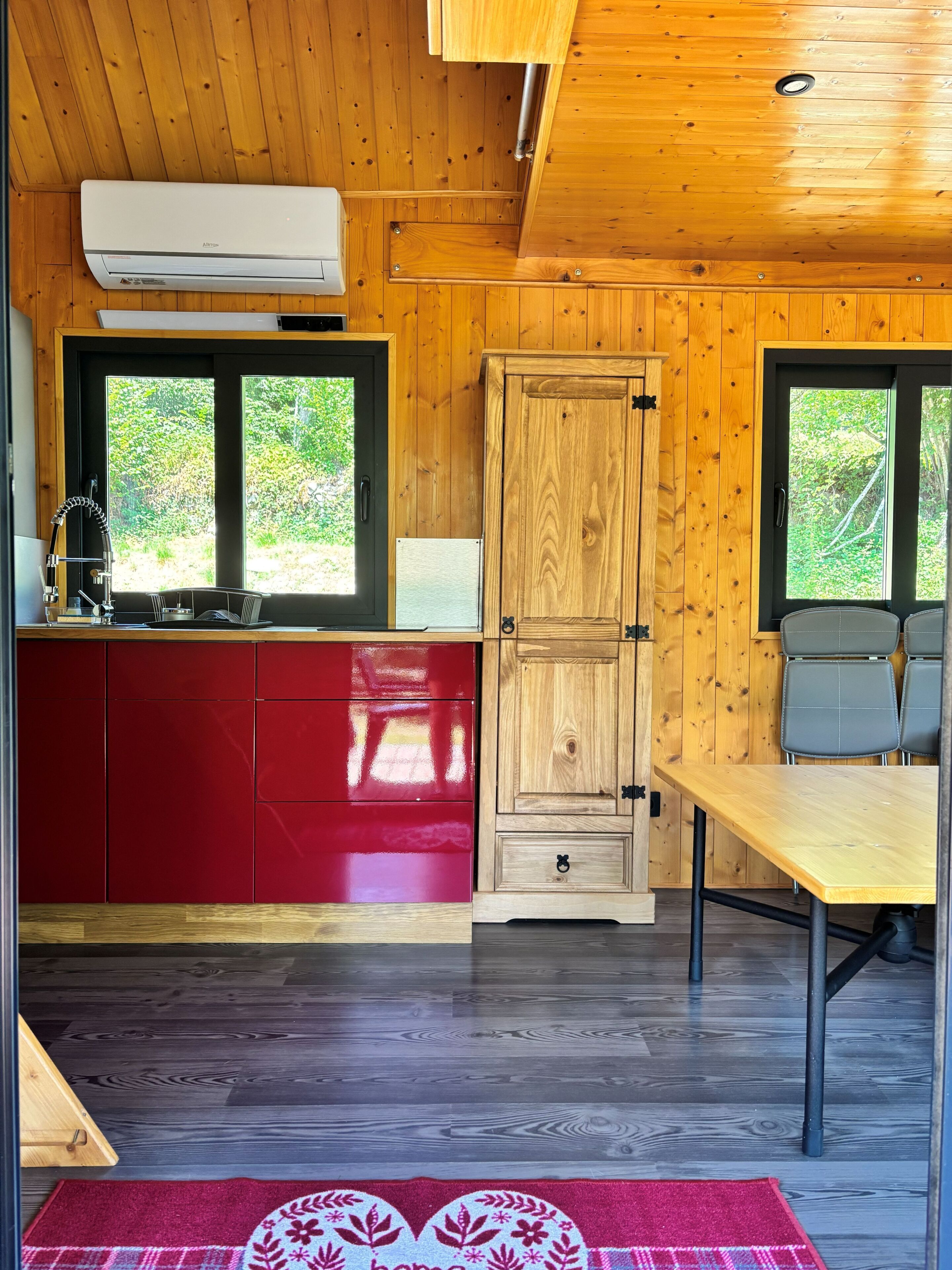 Ein Holzblockhaus-Innenraum mit Küche, Essbereich und einer Tür zu einem Garten.