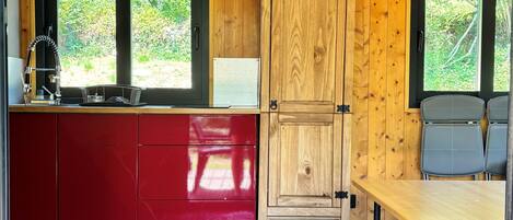 Ein Holzblockhaus-Innenraum mit Küche, Essbereich und einer Tür zu einem Garten.