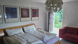 Ein Schlafzimmer mit einem Bett, einem roten Sofa und drei gerahmten Kunstwerken an der Wand.