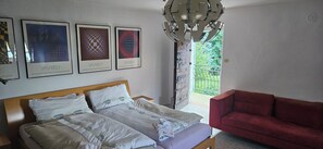 Quarto com uma cama, um sofá vermelho e três obras de arte emolduradas na parede.