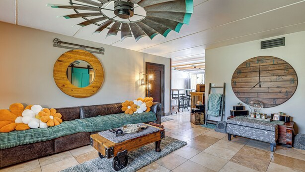 A spacious living area with a large wooden sofa, a coffee table, and a unique ceiling fan. - Private Hot Tub + Patio: Condo By Camelback Mtn! (Phoenix)