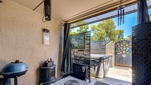 A cozy room with a stone wall, a wood-burning stove, a wicker ottoman, and a view of the outdoors. - Private Hot Tub + Patio: Condo By Camelback Mtn! (Phoenix)