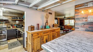 A kitchen with wooden cabinets, a marble countertop, and a dining area with a table and chairs. - Private Hot Tub + Patio: Condo By Camelback Mtn! (Phoenix)