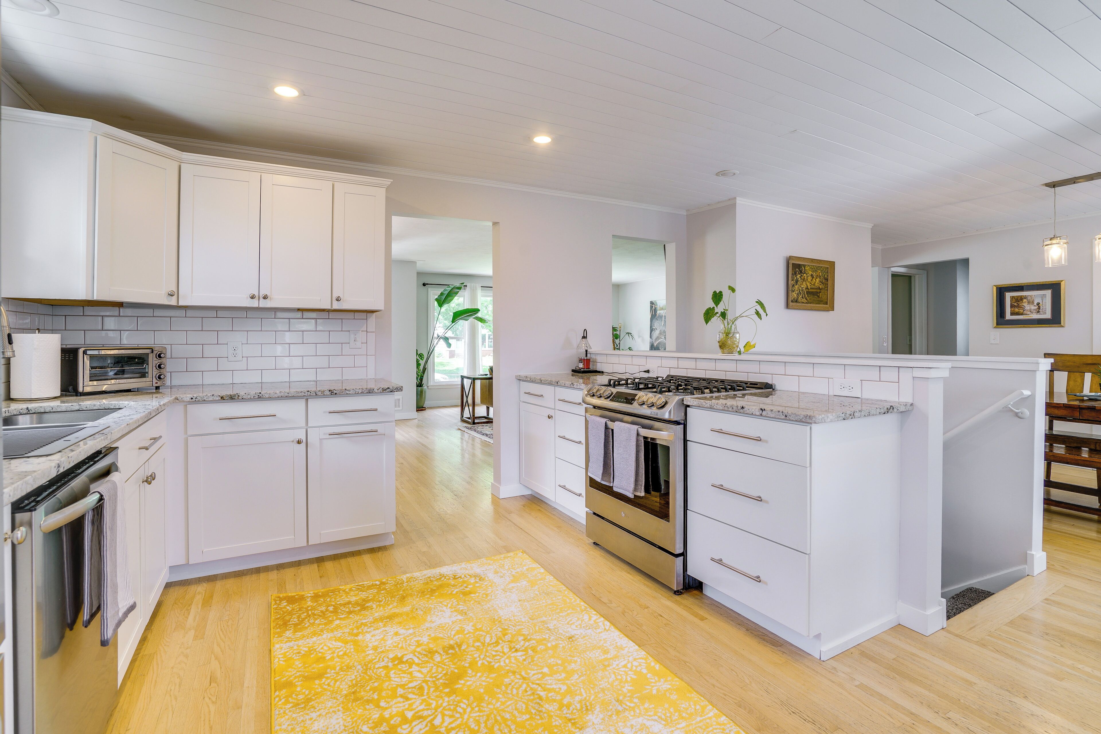 A kitchen with white cabinets, a central island, a stove, and a microwave.