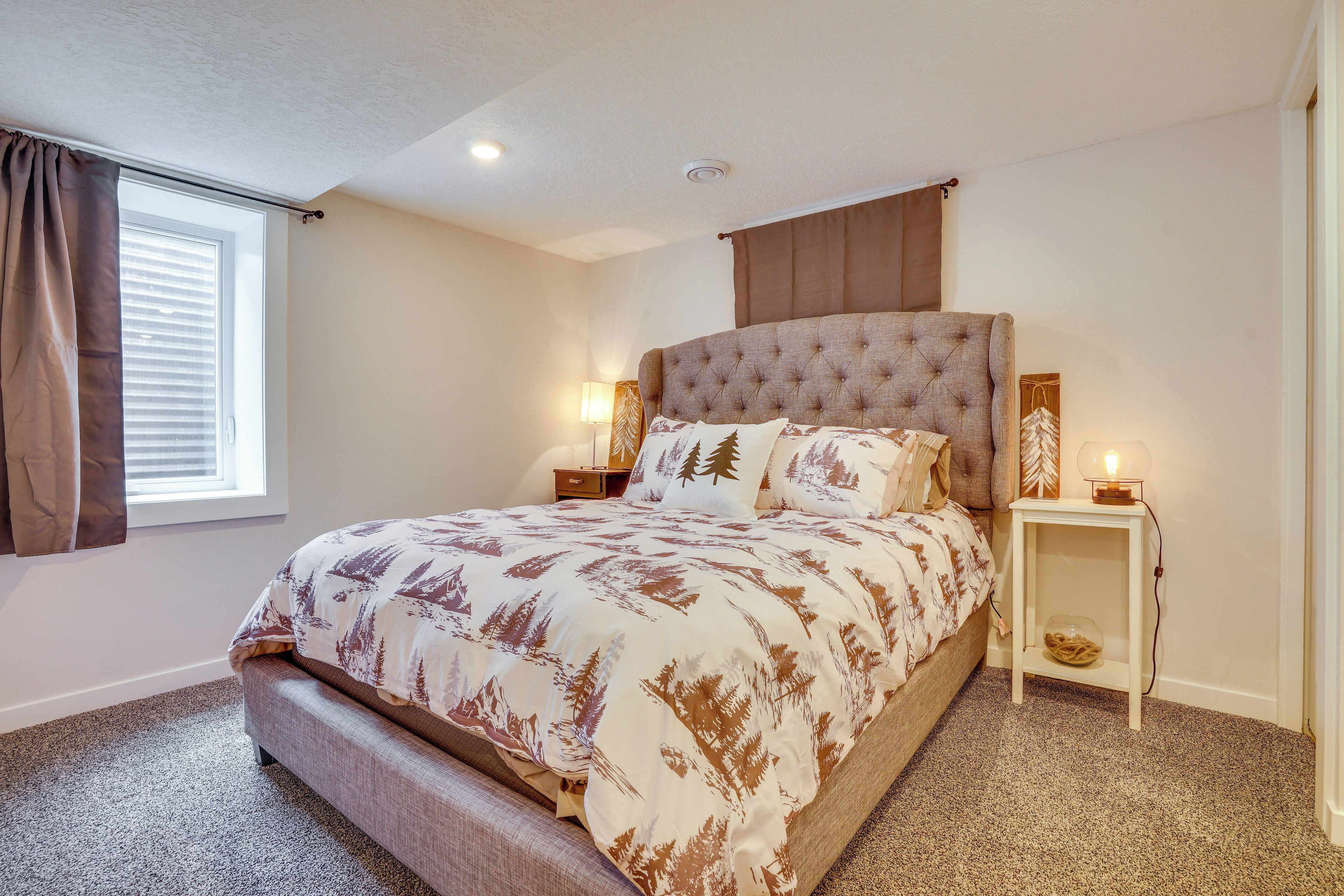 A bedroom with a large bed, two bedside tables, a window with curtains, and a ceiling light.