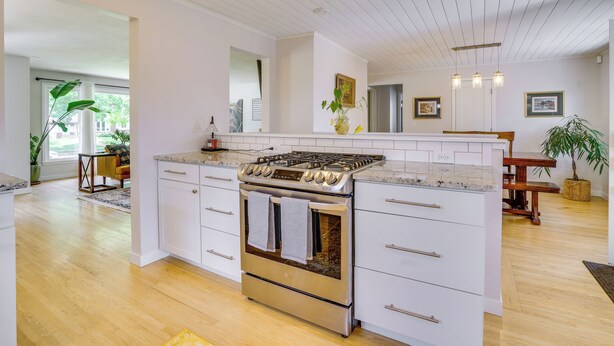 A modern kitchen with a central island, stainless steel appliances, and a wooden dining table.