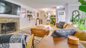 A living room with a fireplace, a sofa, a coffee table, and a TV mounted on the wall.